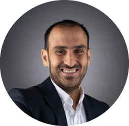 a man wearing a suit and tie smiling and looking at the camera