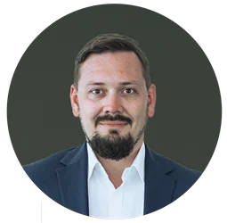 a man wearing a suit and tie smiling and looking at the camera